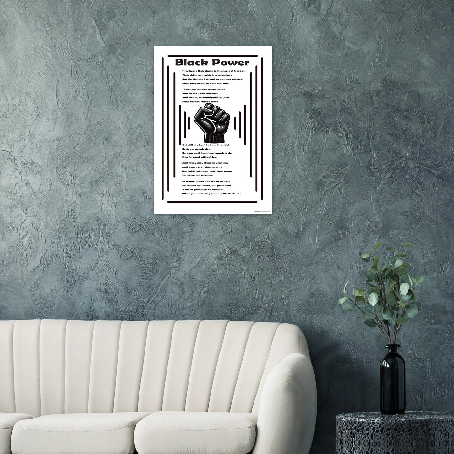 Poster with a black power fist design on a gray wall above a white sofa.