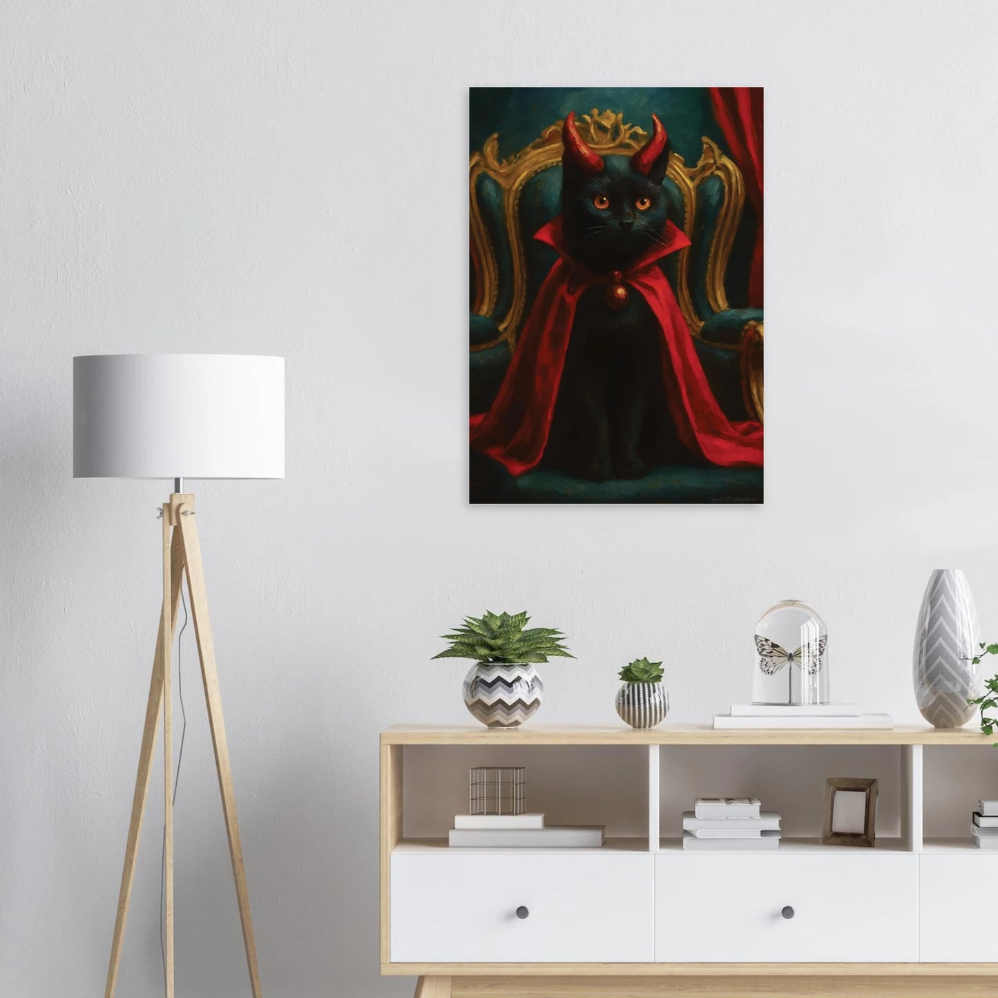 Decorative painting of a black cat with red cape on a wall above a white cabinet with decorative items.